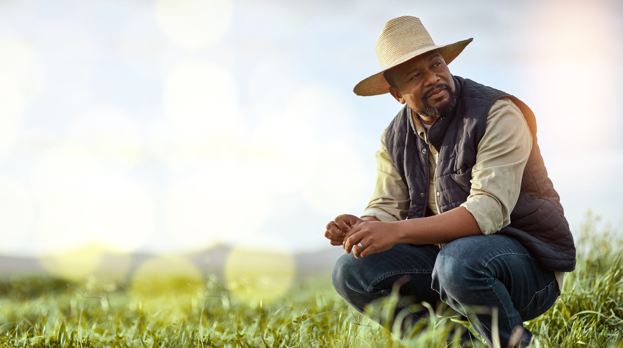 Farmer, black man and mockup for agriculture and sustainability outdoor on an agro farm with bokeh. Person on grass field thinking about farming innovation, growth and ecology in the countryside.